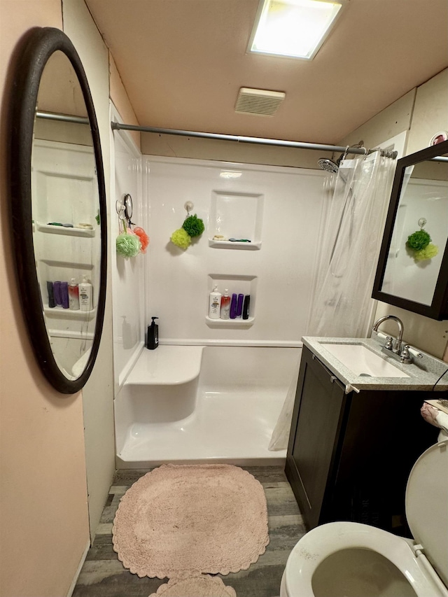 bathroom featuring hardwood / wood-style floors, toilet, vanity, and a shower with shower curtain