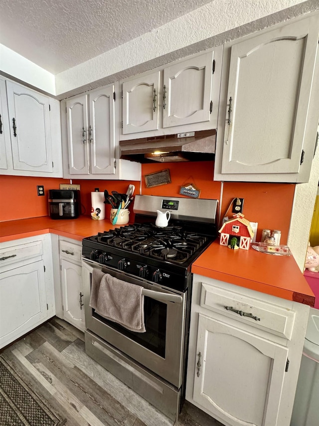 kitchen featuring stainless steel gas range oven, dark hardwood / wood-style flooring, and a textured ceiling