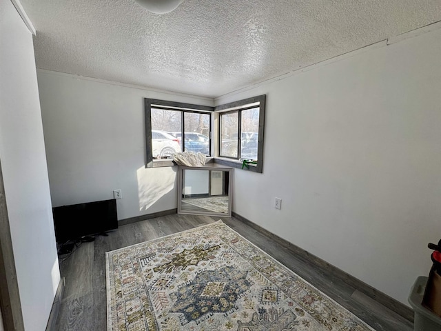 empty room featuring crown molding, dark wood-type flooring, and a textured ceiling