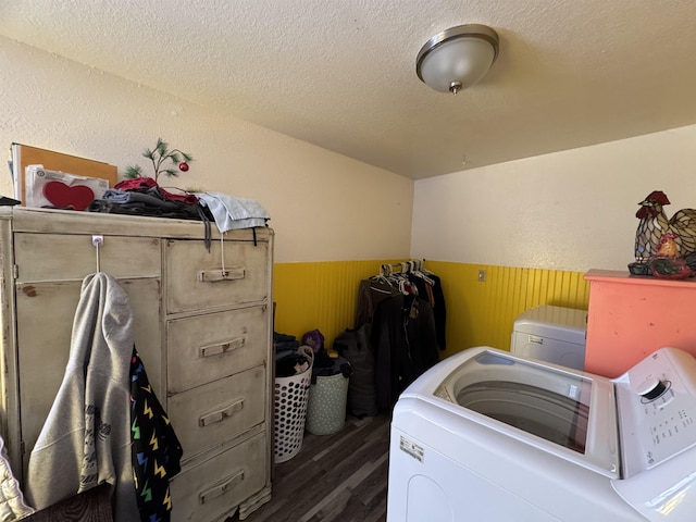 laundry area featuring washing machine and clothes dryer, wood walls, dark wood-type flooring, and a textured ceiling