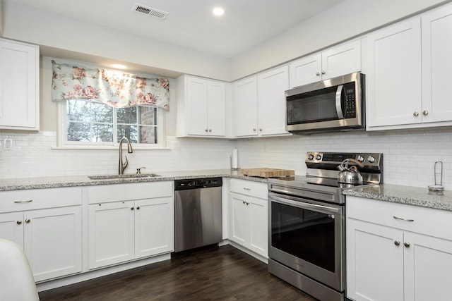 kitchen featuring light stone countertops, white cabinets, appliances with stainless steel finishes, and sink