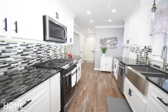 kitchen featuring white cabinetry, hanging light fixtures, ornamental molding, and appliances with stainless steel finishes