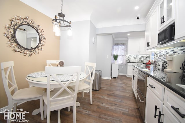 kitchen featuring decorative backsplash, dark wood-type flooring, white cabinets, black microwave, and a notable chandelier