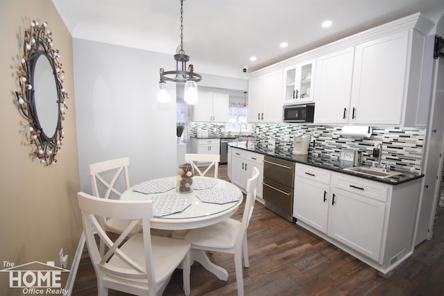 kitchen featuring a sink, stainless steel dishwasher, dark countertops, black microwave, and dark wood-style flooring