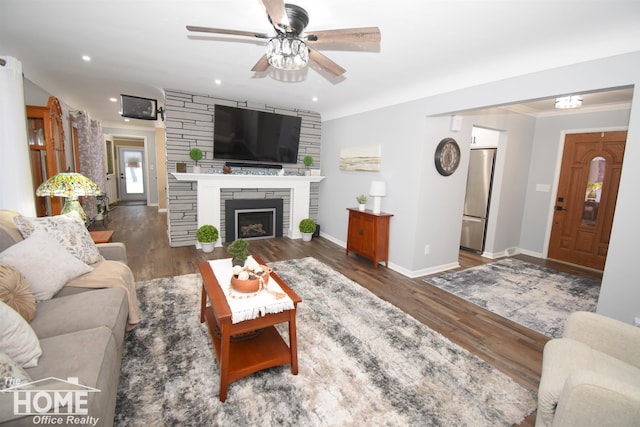 living area with wood finished floors, baseboards, recessed lighting, ceiling fan, and a stone fireplace