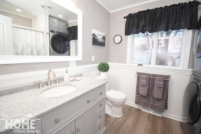 full bath with vanity, wood finished floors, visible vents, stacked washer / drying machine, and toilet