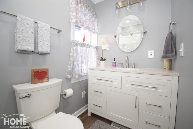 bathroom with visible vents, toilet, wood finished floors, baseboards, and vanity