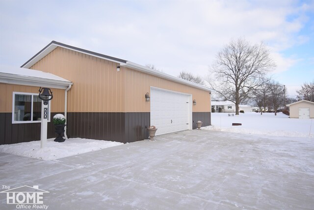 snow covered property with a detached garage