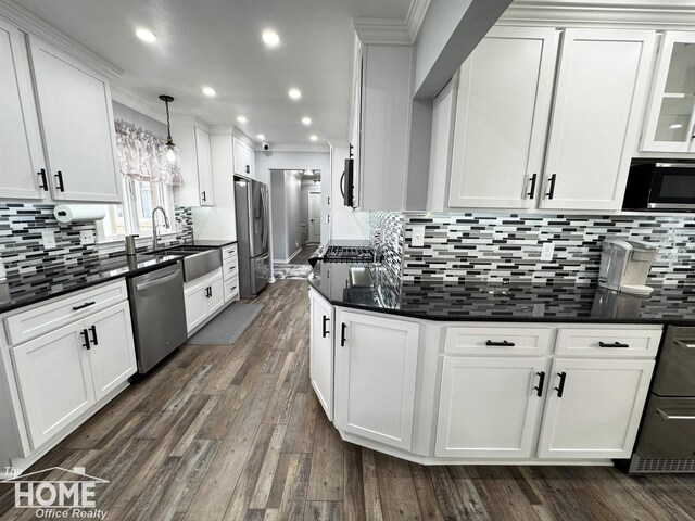 200 Elmwood Dr, Corunna, MI 48817 - kitchen with crown molding, white cabinets, dark countertops, stainless steel appliances, and tasteful backsplash