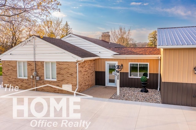 200 Elmwood Dr, Corunna, MI 48817 - exterior space featuring board and batten siding, brick siding, and a chimney