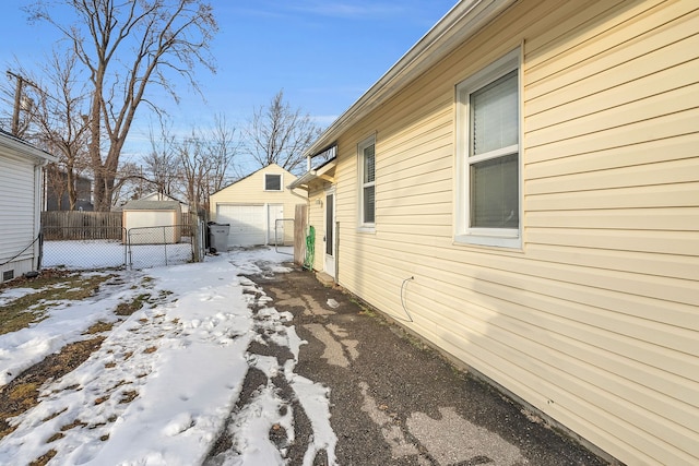 view of snowy exterior featuring an outdoor structure and a garage