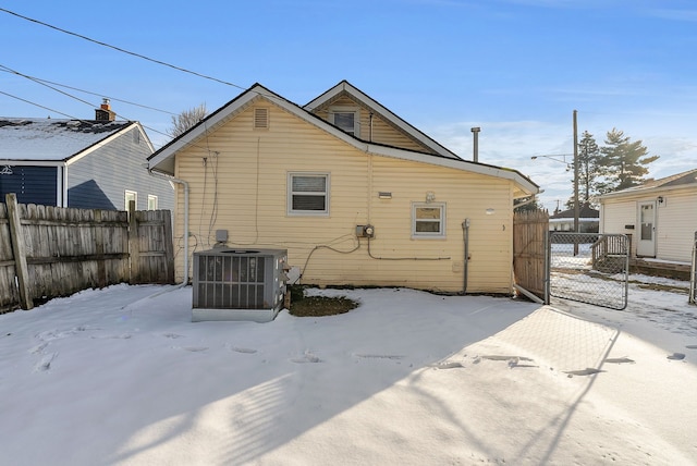 snow covered back of property with central AC