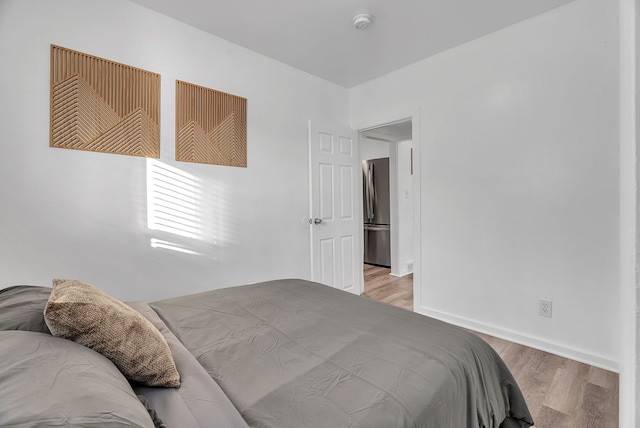 bedroom with light wood-type flooring and stainless steel fridge