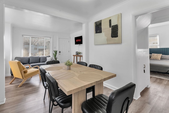 dining area with hardwood / wood-style flooring, a healthy amount of sunlight, and crown molding