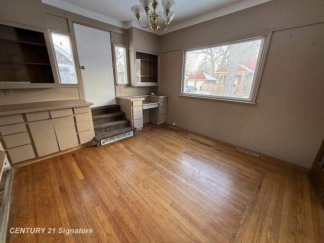 unfurnished dining area with light hardwood / wood-style floors and a notable chandelier