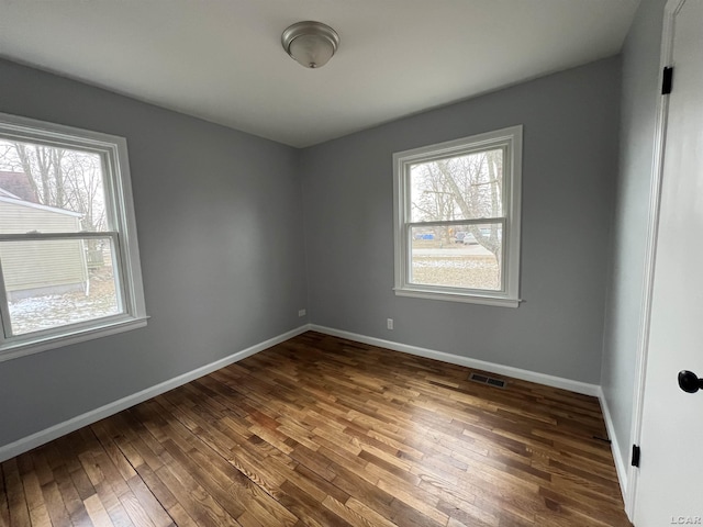 spare room featuring dark wood-type flooring and a wealth of natural light