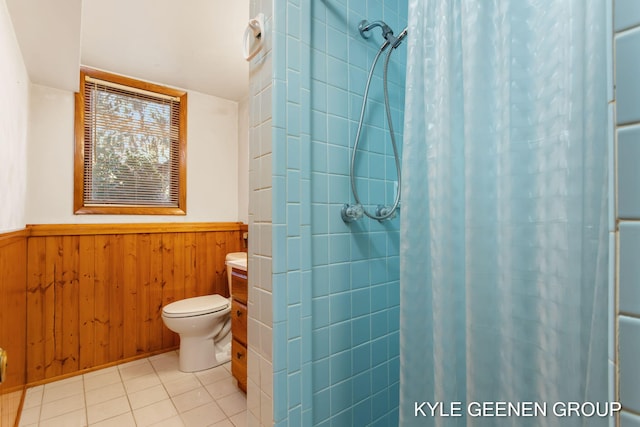 bathroom with tile patterned floors, toilet, wood walls, and curtained shower