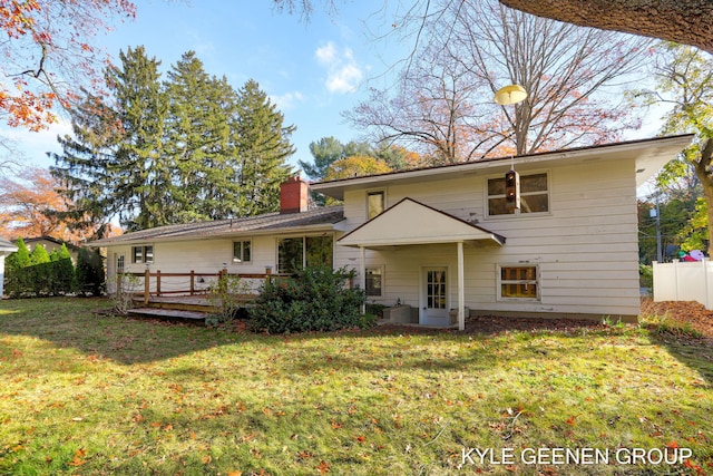 rear view of property featuring a lawn and a deck