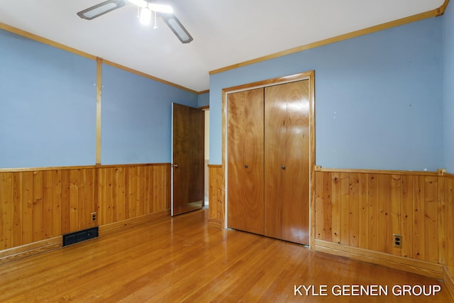 unfurnished bedroom featuring crown molding, light hardwood / wood-style flooring, a closet, and ceiling fan