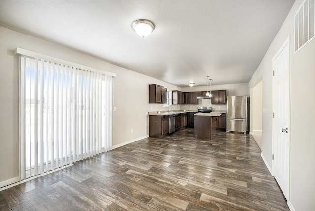 kitchen featuring a center island, appliances with stainless steel finishes, hanging light fixtures, sink, and dark brown cabinetry