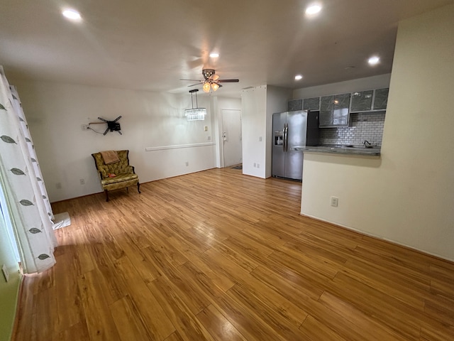 kitchen with tasteful backsplash, wood-type flooring, stainless steel fridge, ceiling fan, and kitchen peninsula