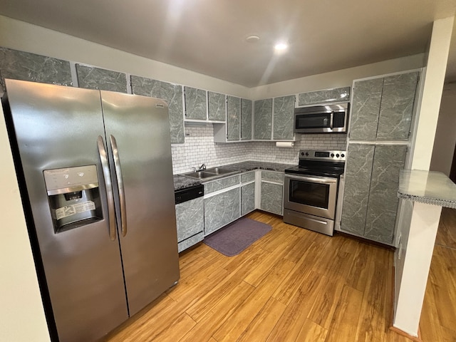 kitchen featuring sink, gray cabinets, appliances with stainless steel finishes, tasteful backsplash, and light hardwood / wood-style floors