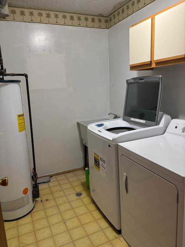 laundry area with cabinets, washing machine and clothes dryer, a textured ceiling, and gas water heater