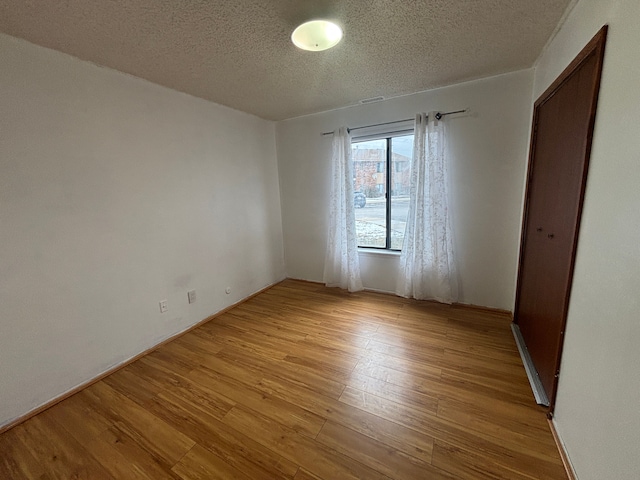 spare room with light hardwood / wood-style floors and a textured ceiling