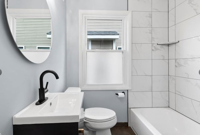 full bathroom with plenty of natural light, toilet, vanity, and tiled shower / bath