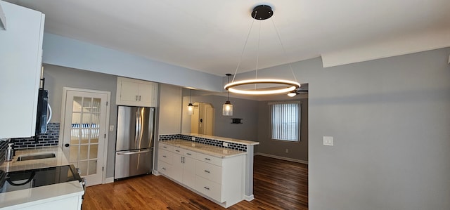 kitchen featuring kitchen peninsula, backsplash, white cabinetry, and stainless steel appliances