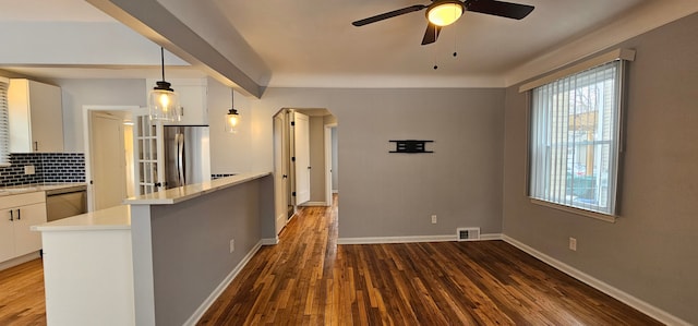 kitchen featuring pendant lighting, dark hardwood / wood-style flooring, appliances with stainless steel finishes, backsplash, and white cabinets