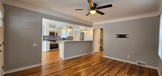 kitchen featuring kitchen peninsula, hanging light fixtures, appliances with stainless steel finishes, white cabinets, and decorative backsplash