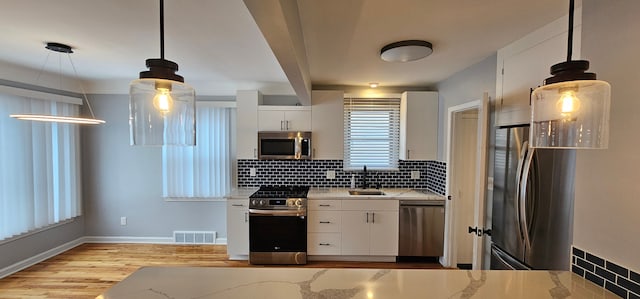 kitchen with white cabinets, stainless steel appliances, and pendant lighting