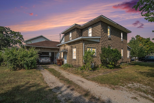 property exterior at dusk featuring a carport and a lawn