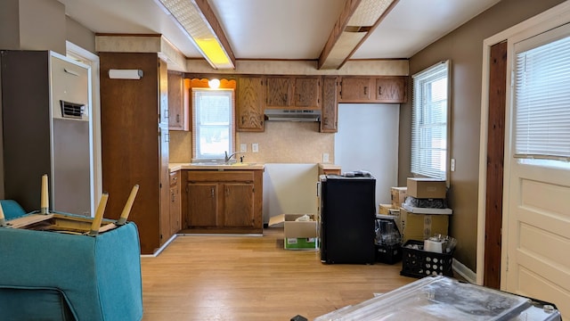 kitchen featuring sink, beamed ceiling, and light wood-type flooring