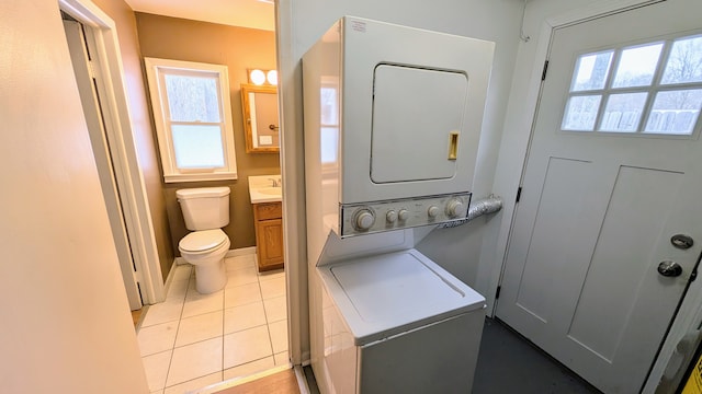 washroom with a healthy amount of sunlight, light tile patterned floors, and stacked washer / dryer