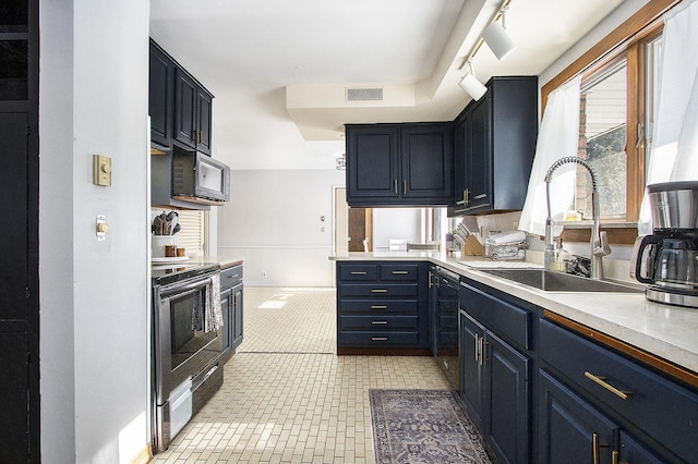 kitchen with black appliances, light tile patterned floors, sink, blue cabinets, and track lighting