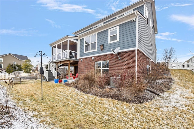 back of property featuring a sunroom and a lawn