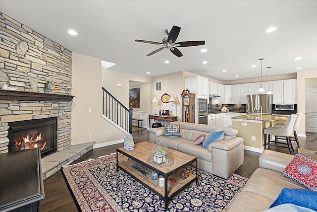 living room featuring ceiling fan, dark hardwood / wood-style floors, and a fireplace