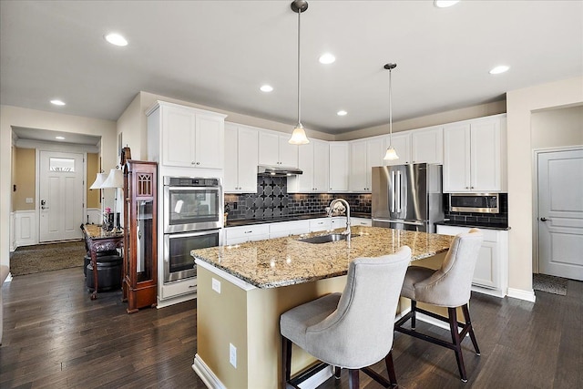 kitchen featuring pendant lighting, an island with sink, white cabinetry, sink, and stainless steel appliances