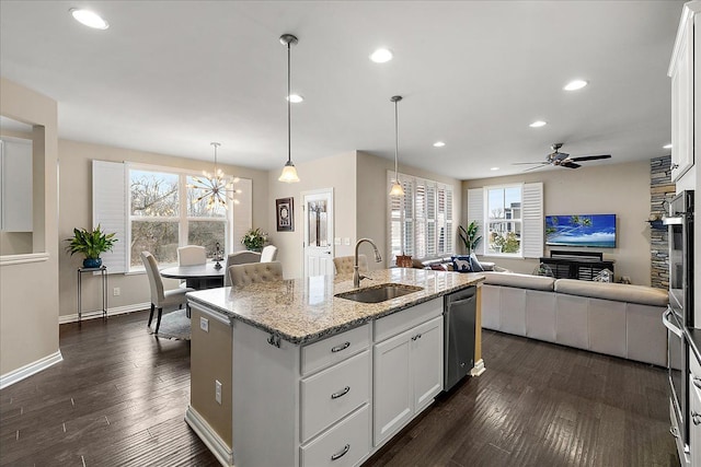 kitchen with white cabinetry, light stone countertops, sink, and a center island with sink