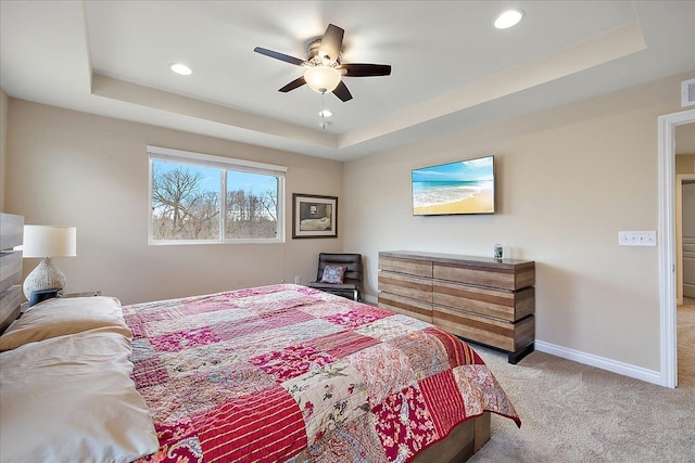 carpeted bedroom with a raised ceiling and ceiling fan