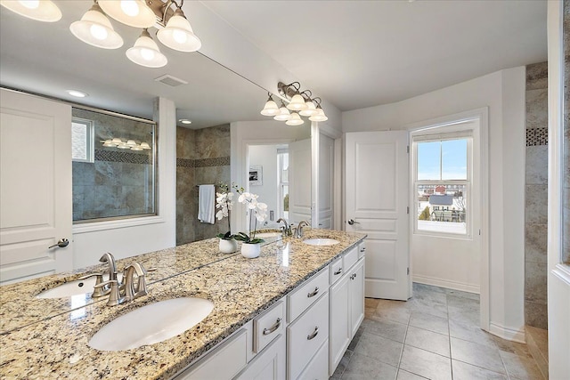 bathroom with tile patterned flooring, vanity, and tiled shower