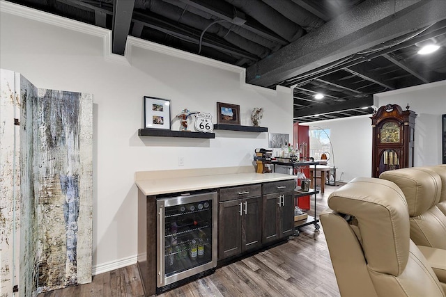 bar featuring wine cooler, hardwood / wood-style floors, and dark brown cabinets