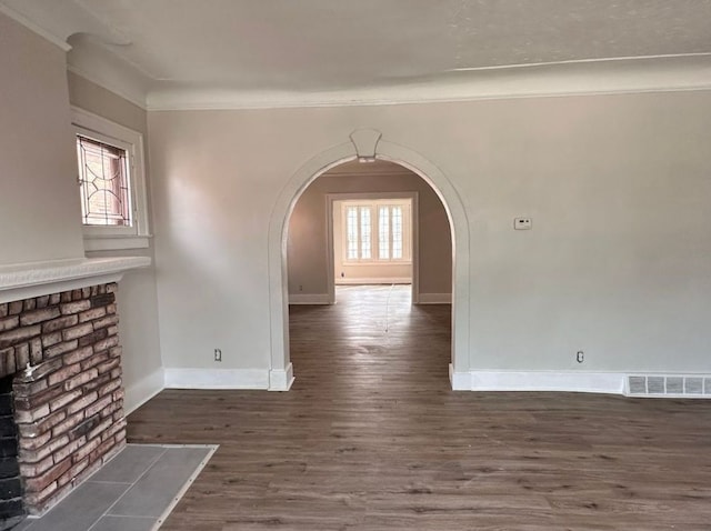 unfurnished living room featuring dark hardwood / wood-style floors, ornamental molding, and a fireplace