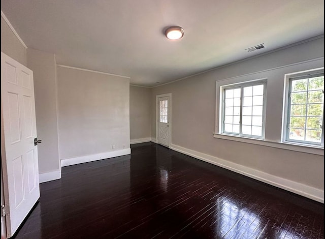 empty room featuring a wealth of natural light, crown molding, and dark wood-type flooring