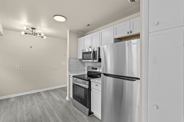 kitchen with decorative backsplash, white cabinets, appliances with stainless steel finishes, and light hardwood / wood-style flooring