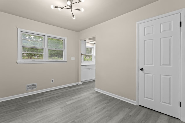 spare room with light wood-type flooring and an inviting chandelier