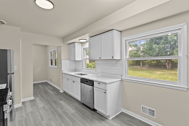 kitchen featuring backsplash, white cabinets, light hardwood / wood-style flooring, and stainless steel appliances