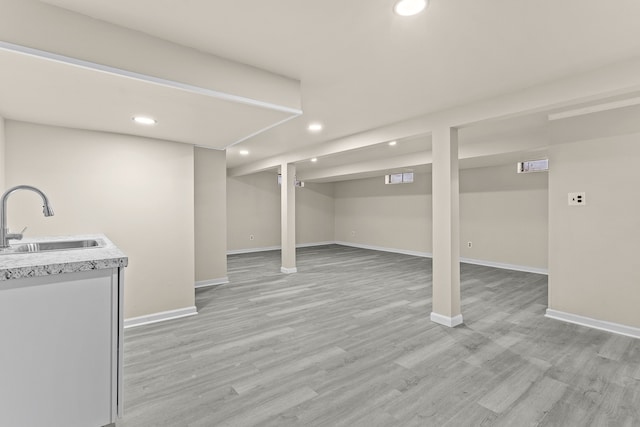 basement featuring sink and light wood-type flooring